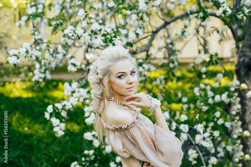 Beautiful young girl in an apple blossoming garden