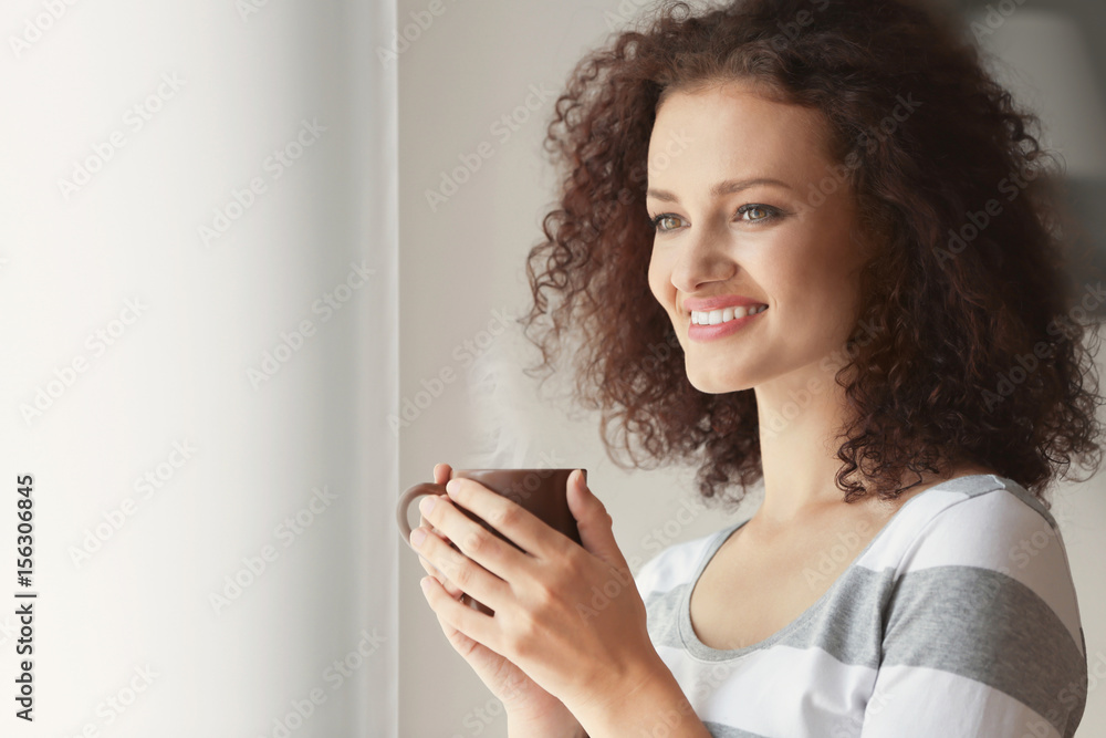 Young woman holding cup of coffee and looking at window Young woman holding cup of coffee and looking at window