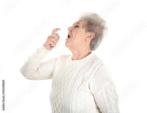 Senior ill woman using spra...