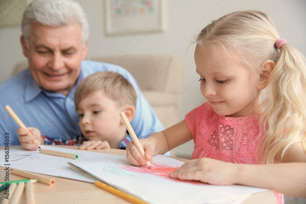 Cute little girl painting together with her brother and grandfather Cute little girl painting together with her brother and grandfather