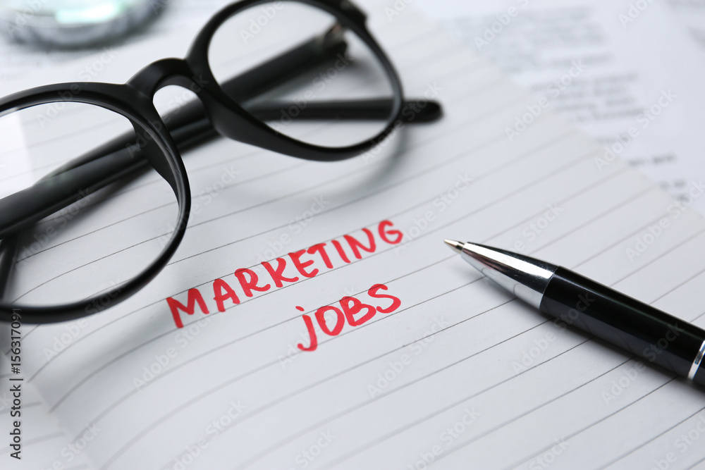 Open notebook with text MARKETING JOBS, closeup Open notebook with text MARKETING JOBS, closeup