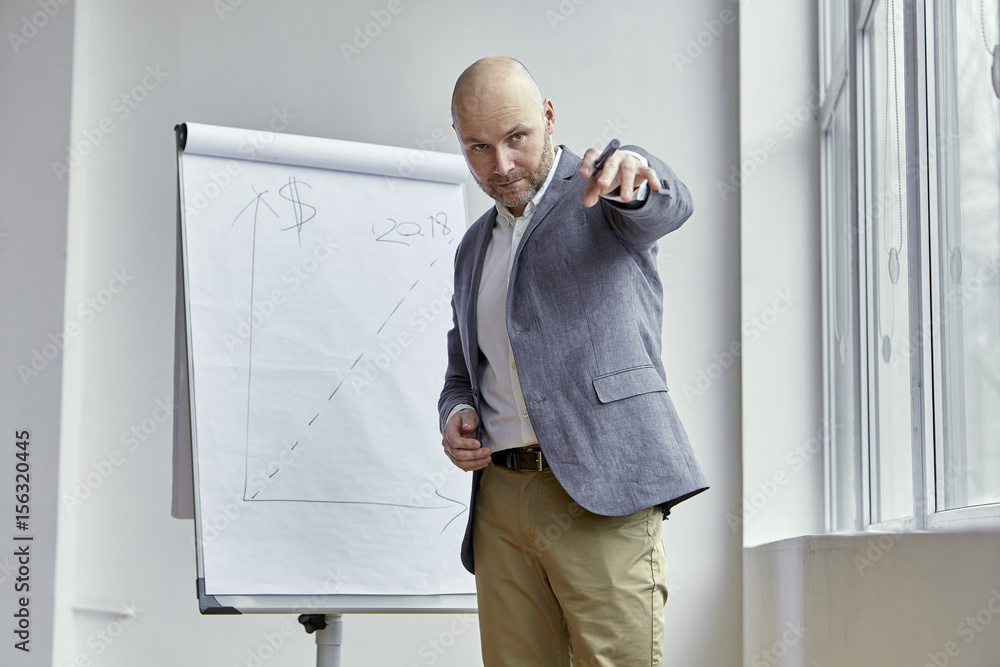 Fototapeta premium Bald Businessman Poiting at Something With a Marker