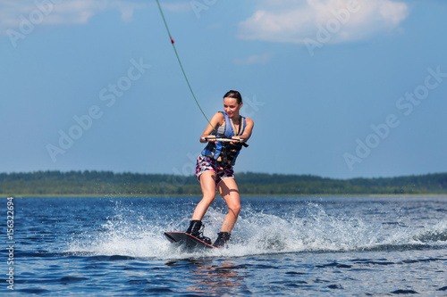 slim woman riding wakeboard on wave of boat © AnnaMoskvina