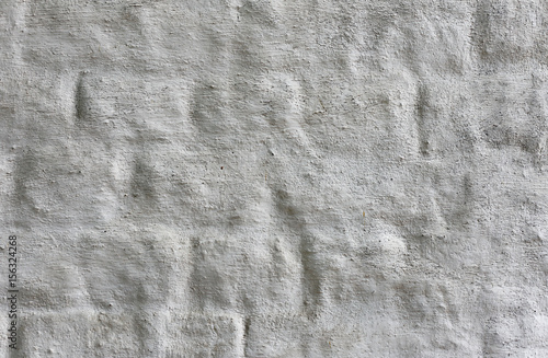 Ancient white brick wall with a thick layer of plaster