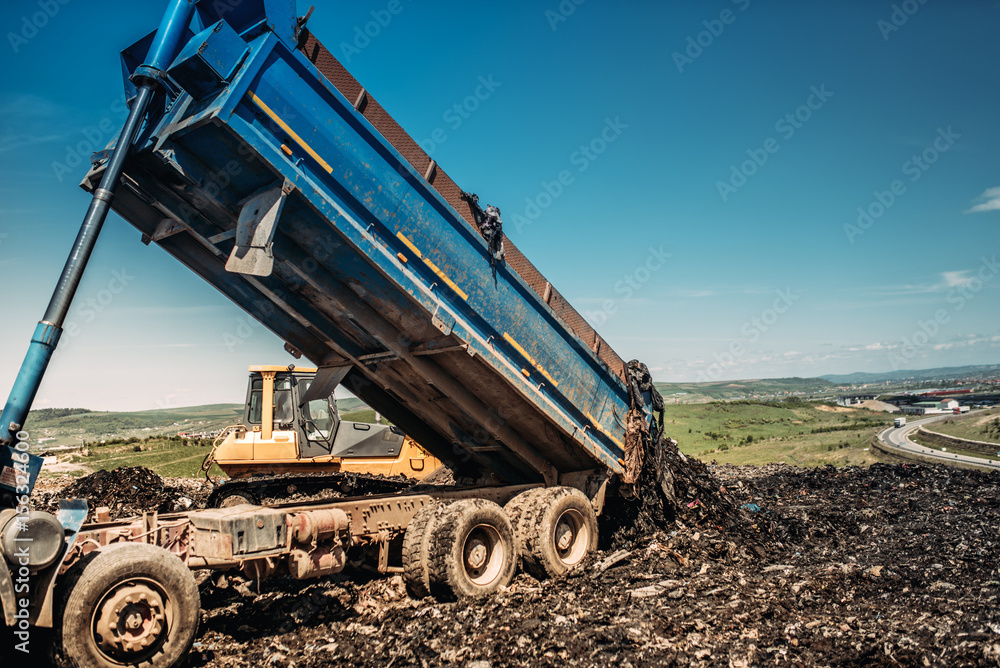 Fototapeta premium industrial dumper trucks unloading garbage into trash hill