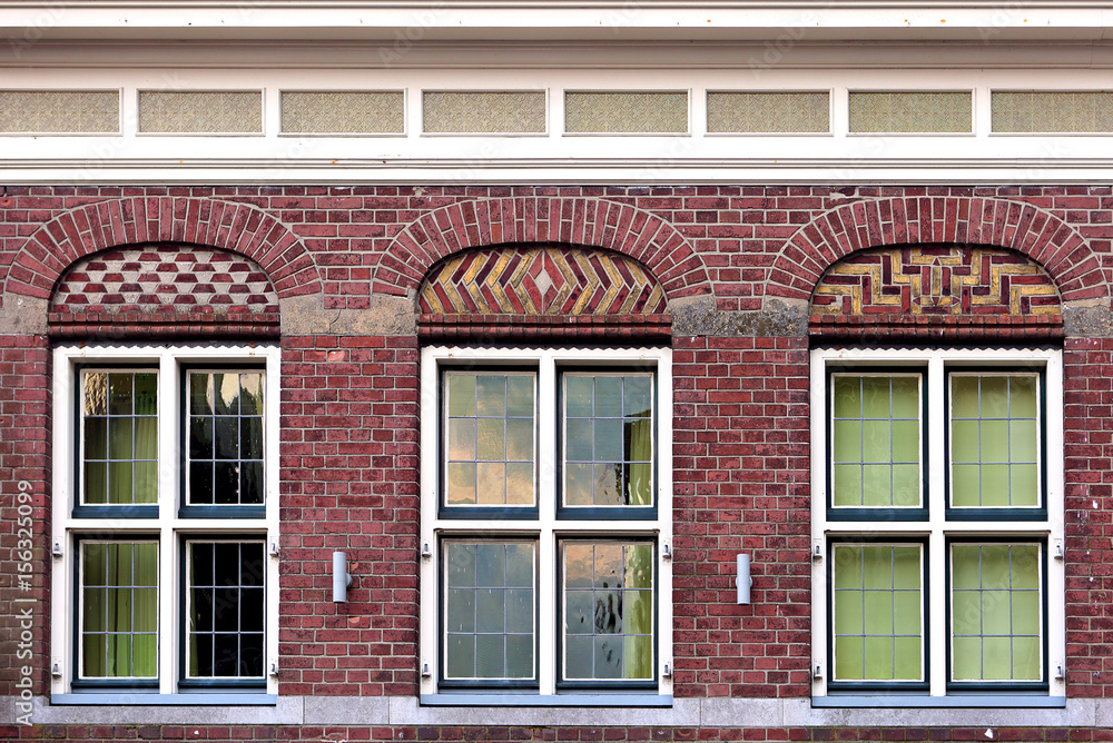 Front beautiful old flat house facade pattern from red brick with white window frame. Vintage building. Netherlands