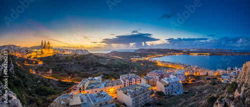 Il-Mellieha, Malta - Beautiful panoramic skyline view of Mellieha town at blue hour with Paris Church and Mellieha beach and Gozo at background with blue sky and clouds photo