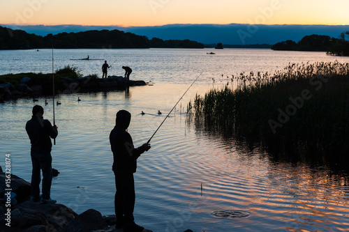Silhouettes of fishermen on the edge of a lake at sunset in Killarney national park
