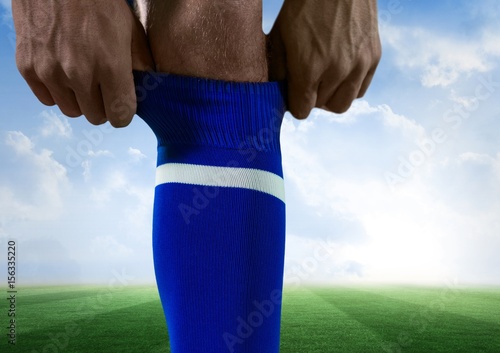 soccer player putting well his blue shock, sky and field back