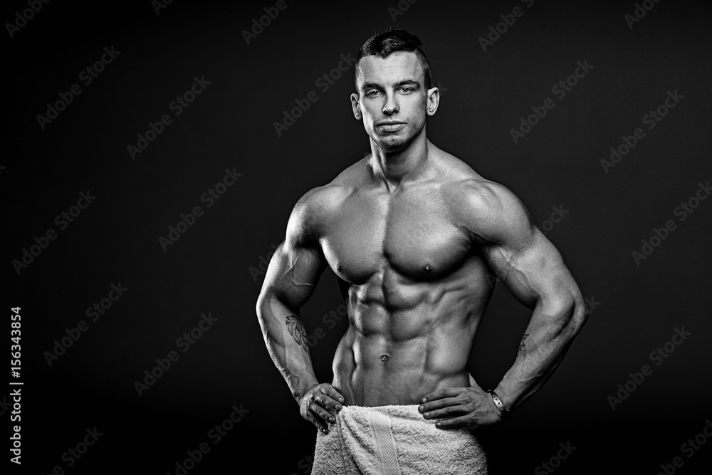 Black and white photo of Muscular and fit young fitness model posing over black background. Black and white photo of Muscular and fit young fitness model posing over black background.