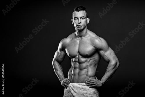Black and white photo of Muscular and fit young fitness model posing over black background.
