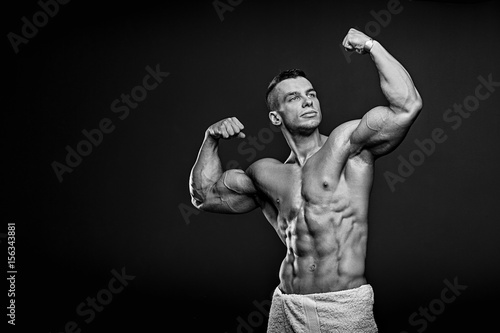 Black and white photo of Muscular and fit young fitness model posing over black background.