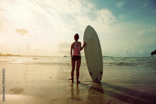 young woman surfer with surfboard on a beach © lzf