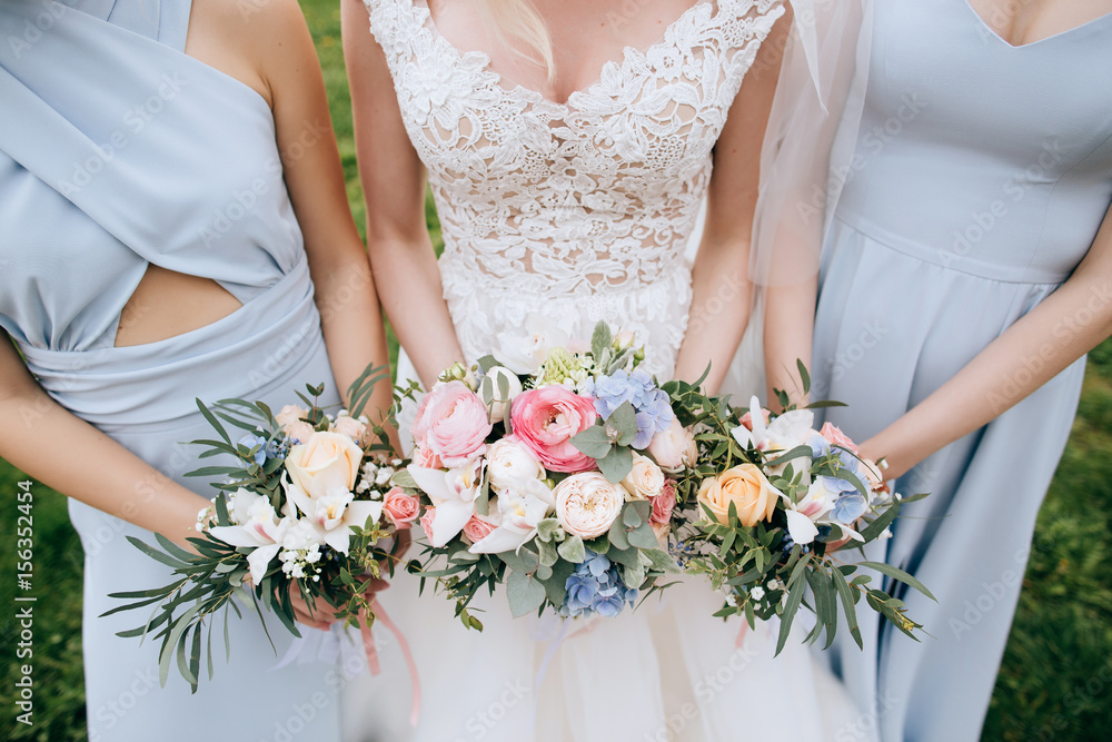 Bride and bridesmaid holding in the hands bouquets of beautiful fresh flowers