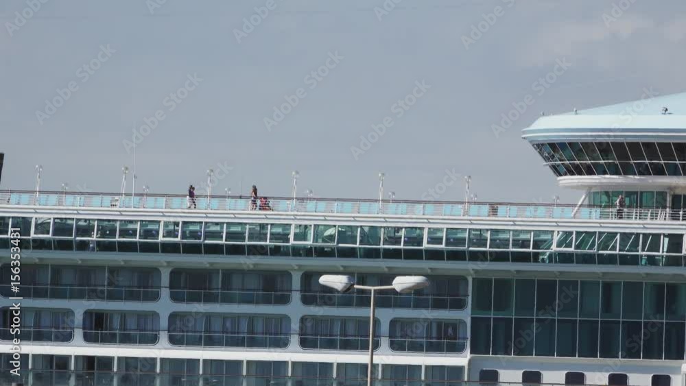 Long shot of top of ocean liner with tourists walking Long shot of top of ocean liner with tourists walking
