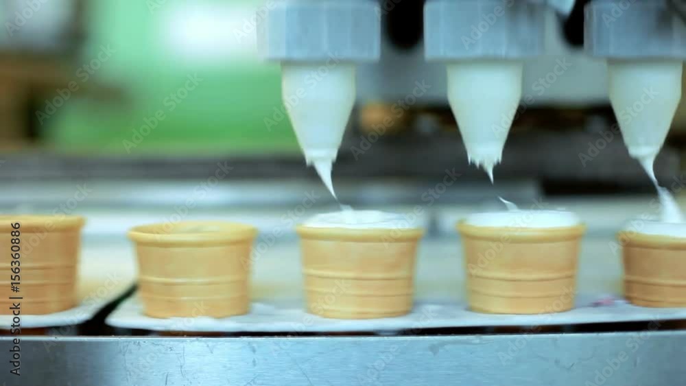 Ice cream pouring in waffle cones. Automated production line at food