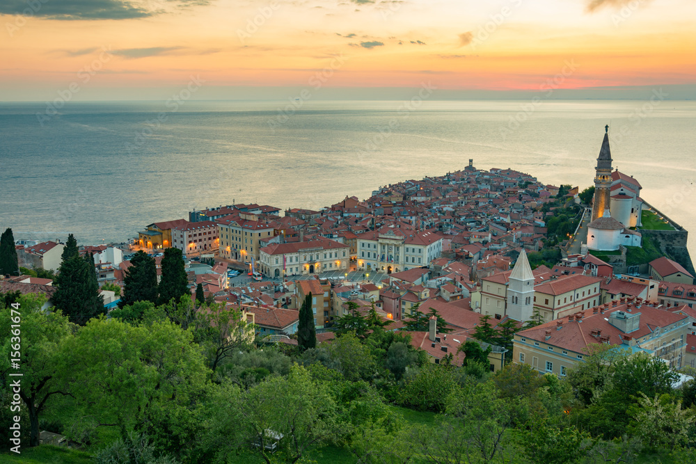 View from the city walls of the church and town Piran as lights turn just little after the sunset