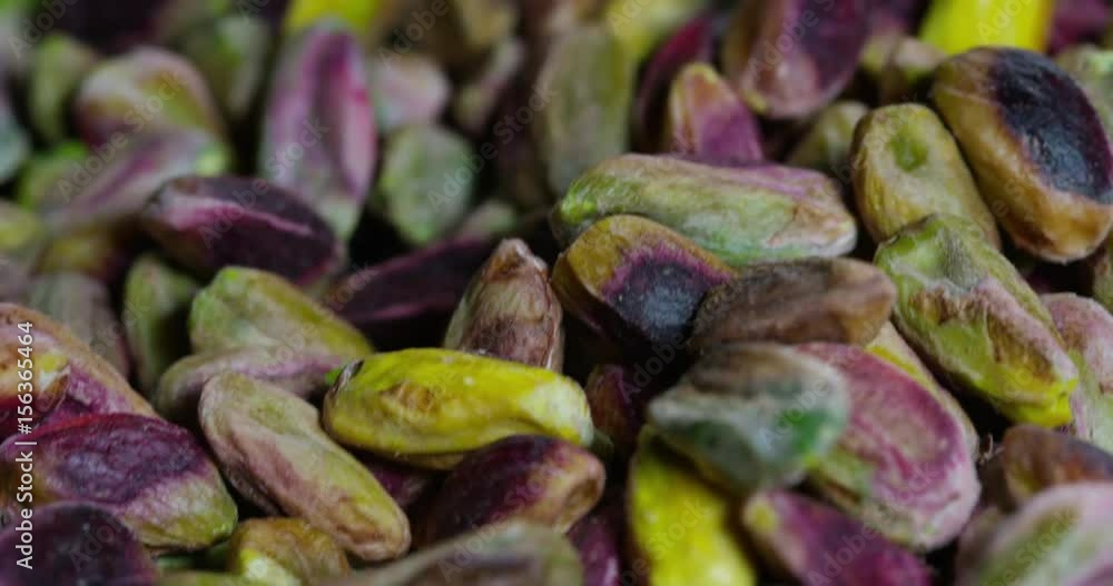 Man touches colorful cleaned pistachio, green, purple, yellow. Concept: salted, nuts, seeds, delicious, healthy, growing on the Man touches colorful cleaned pistachio, green, purple, yellow. Concept: salted, nuts, seeds, delicious, healthy, growing on the