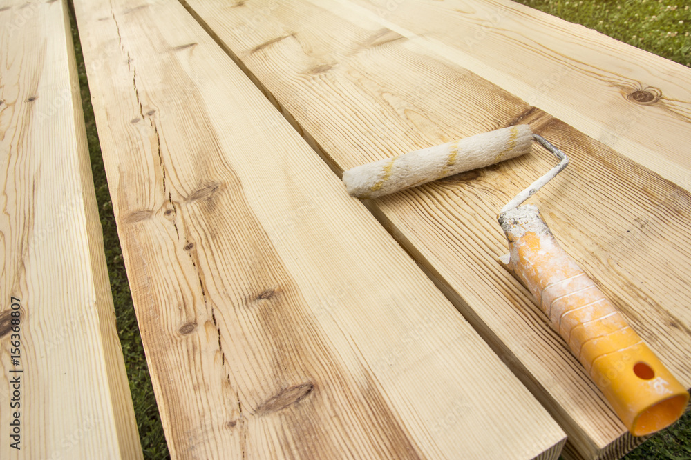 Paint and brush on the wooden background. Preparations for whitewashing of a wooden table.