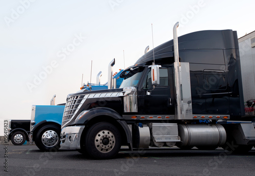 Commercial modern and classic semi trucks in truck stop line