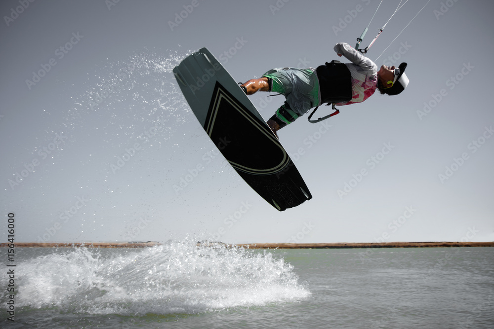 Professional kite boarding rider sportsman jumps high acrobatics kiteboarding front rotation