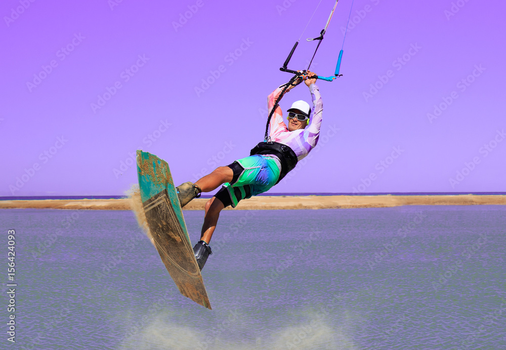 Professional kite boarding rider sportsman jumps high acrobatics kiteboarding trick with front