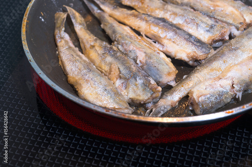 Small wild Fish fried in pan on electric stove