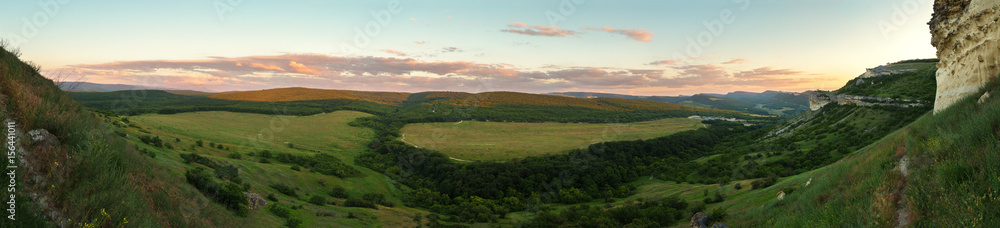 Evening panorama of the green valley. View from the top of cave city Bakla in Crimea.