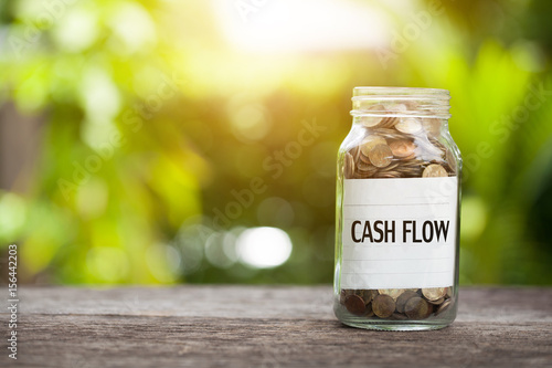 Photography cash flow word with coin in glass jar on wooden table.