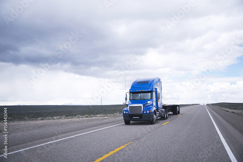 Flat bed semi-truck going to destination point for cargo