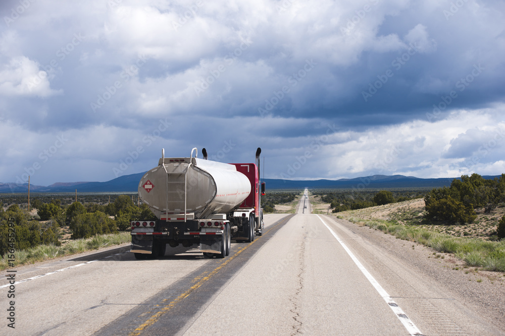 Fototapeta premium Speed up red semi truck rig with tank trailer on long road in Nevada