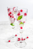 frozen red berries in ice cubes with mint in glasses on stone background