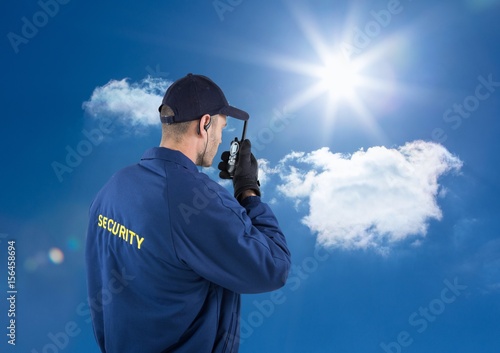 Rear view of security guard talking on walkie talkie against sky