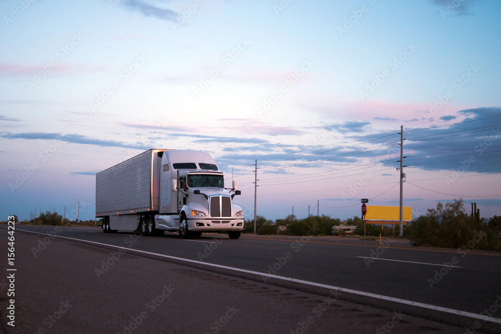Semi truck trailer going on Arizona road in sunset