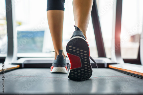 weight of toe of woman press down on the belt of treadmill while jogging in gymnasium