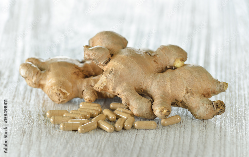 Fresh ginger root and capsules on wooden background Fresh ginger root and capsules on wooden background