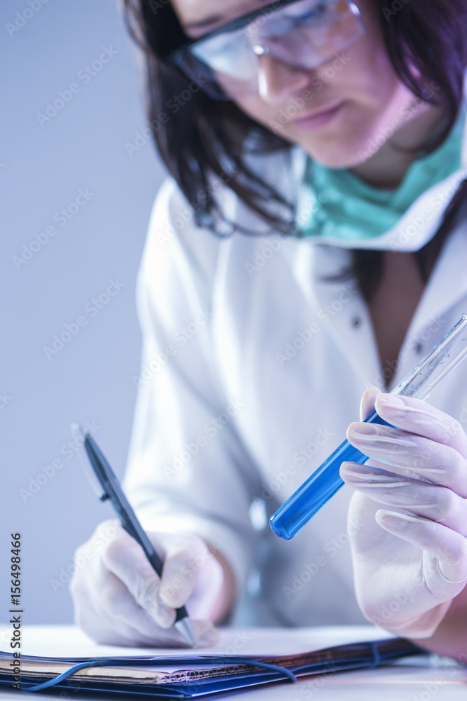 Medical Concepts. Female Laboratory Worker Dealing With Flask Containing Liquid Chemicals Using Protective Gloves. Medical Concepts. Female Laboratory Worker Dealing With Flask Containing Liquid Chemicals Using Protective Gloves.