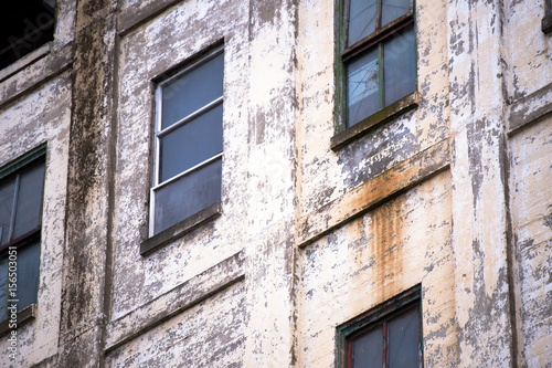 Wall of the old industrial building with windows and shabby paint