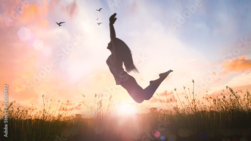 World mental health day concept: Silhouette of a girl jumping at autumn sunset meadow with her hands raised photo