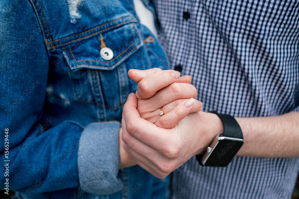 Hands of a couple in love. Man and woman are standing embracing and holding hands