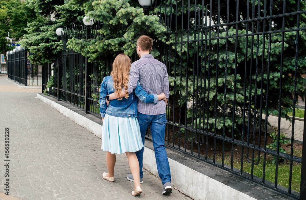 Obraz premium Loving couple embracing and walking through the city, back view