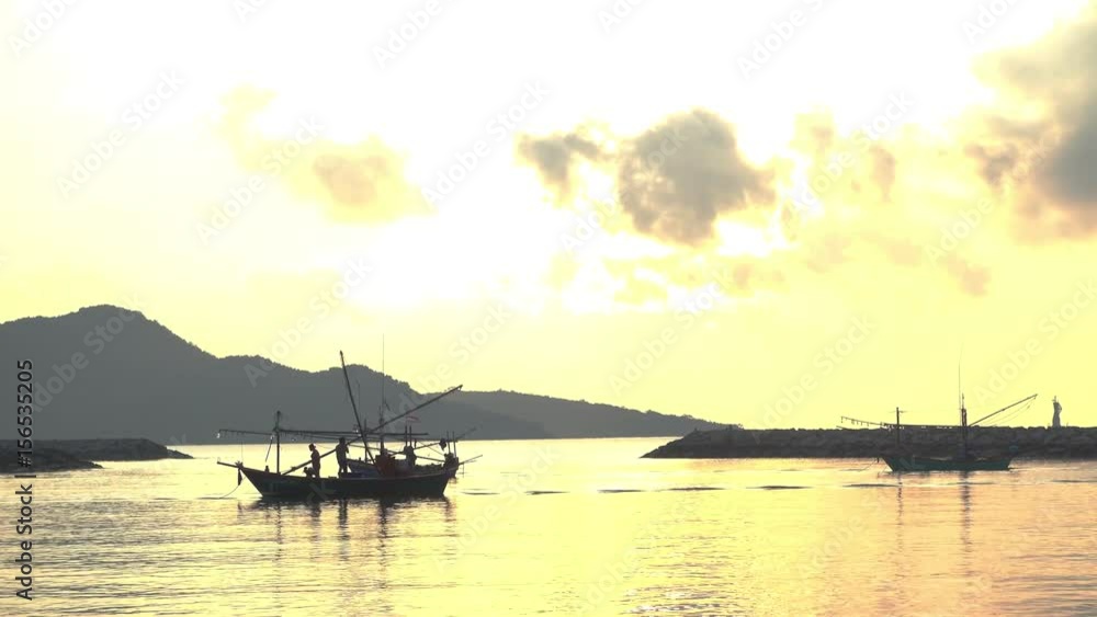 fisherman working on boat over the sea and Mountain in background under sunset or sun rise fisherman working on boat over the sea and Mountain in background under sunset or sun rise