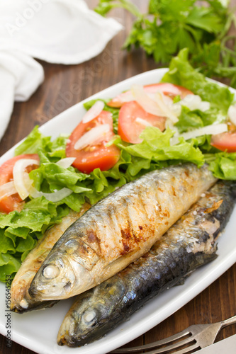 grilled sardines with salad on white dish