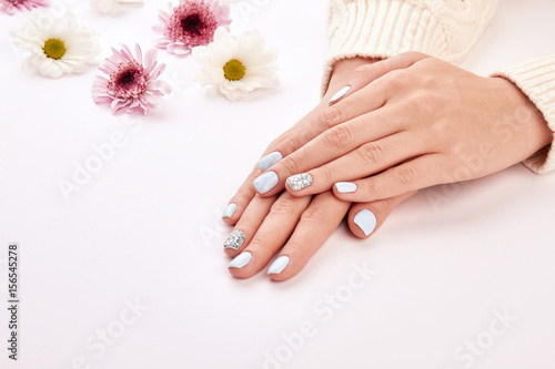 Delicate woman s manicure on a white background.