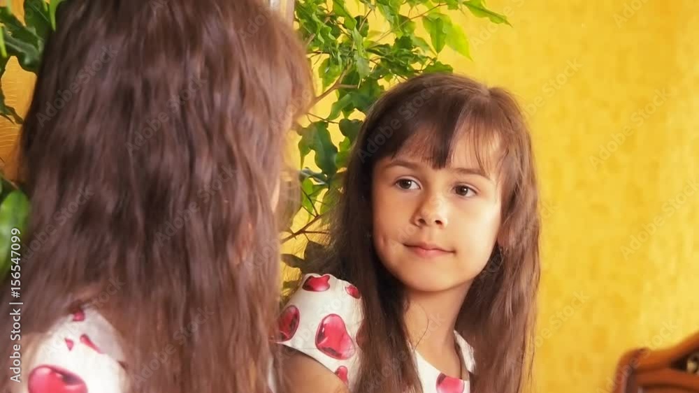 The girl is looking in the mirror. The child at the mirror adjusts his hair. The girl is looking in the mirror. The child at the mirror adjusts his hair.