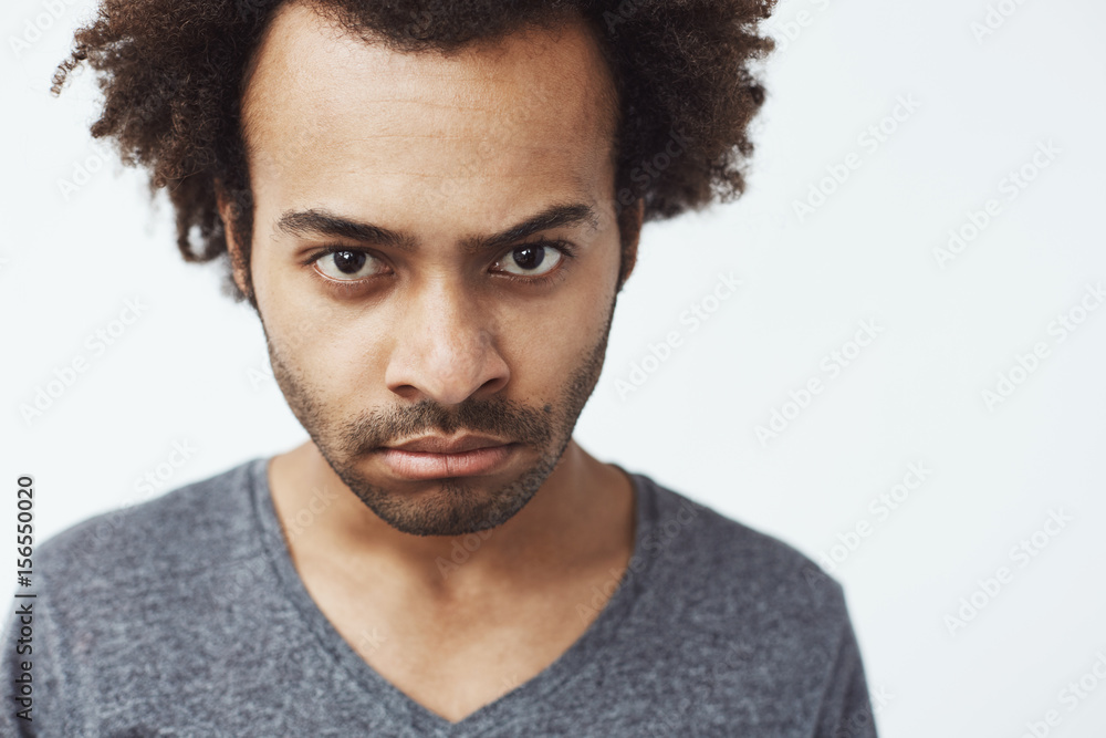 Close up of displeased african man looking at camera brutally. White background. Close up of displeased african man looking at camera brutally. White background.