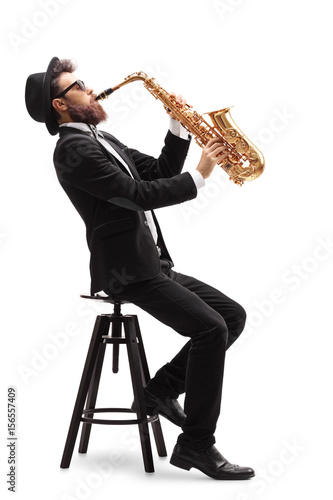 Jazz musician seated on a chair playing a saxophone photo