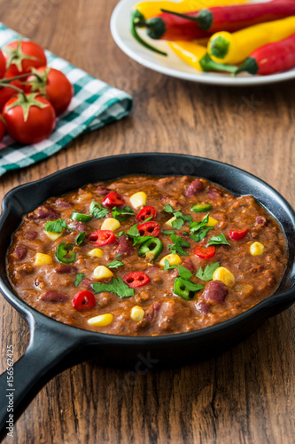 Traditional mexican tex mex chili con carne in a frying pan on wooden table 