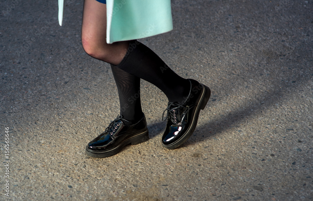 Beautiful young female legs in black elegant shoes on asphalt Beautiful young female legs in black elegant shoes on asphalt