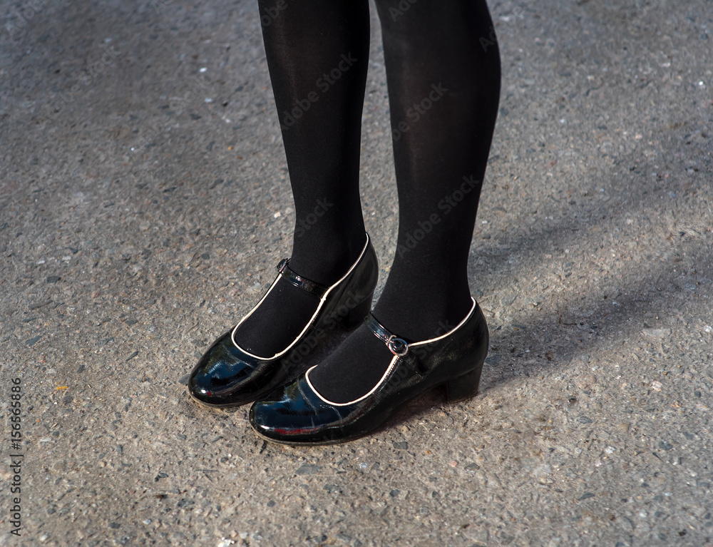 Beautiful young female legs in black elegant shoes on asphalt Beautiful young female legs in black elegant shoes on asphalt